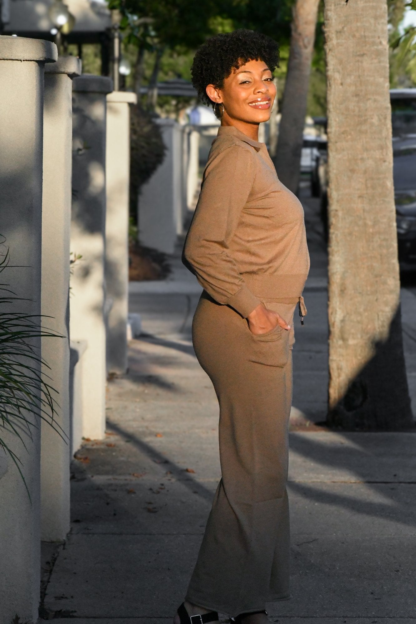 Woman wearing a soft knit two-piece lounge set featuring a collared sweater top and matching drawstring pants. Stylish and cozy outfit for everyday wear, lounging, or travel.