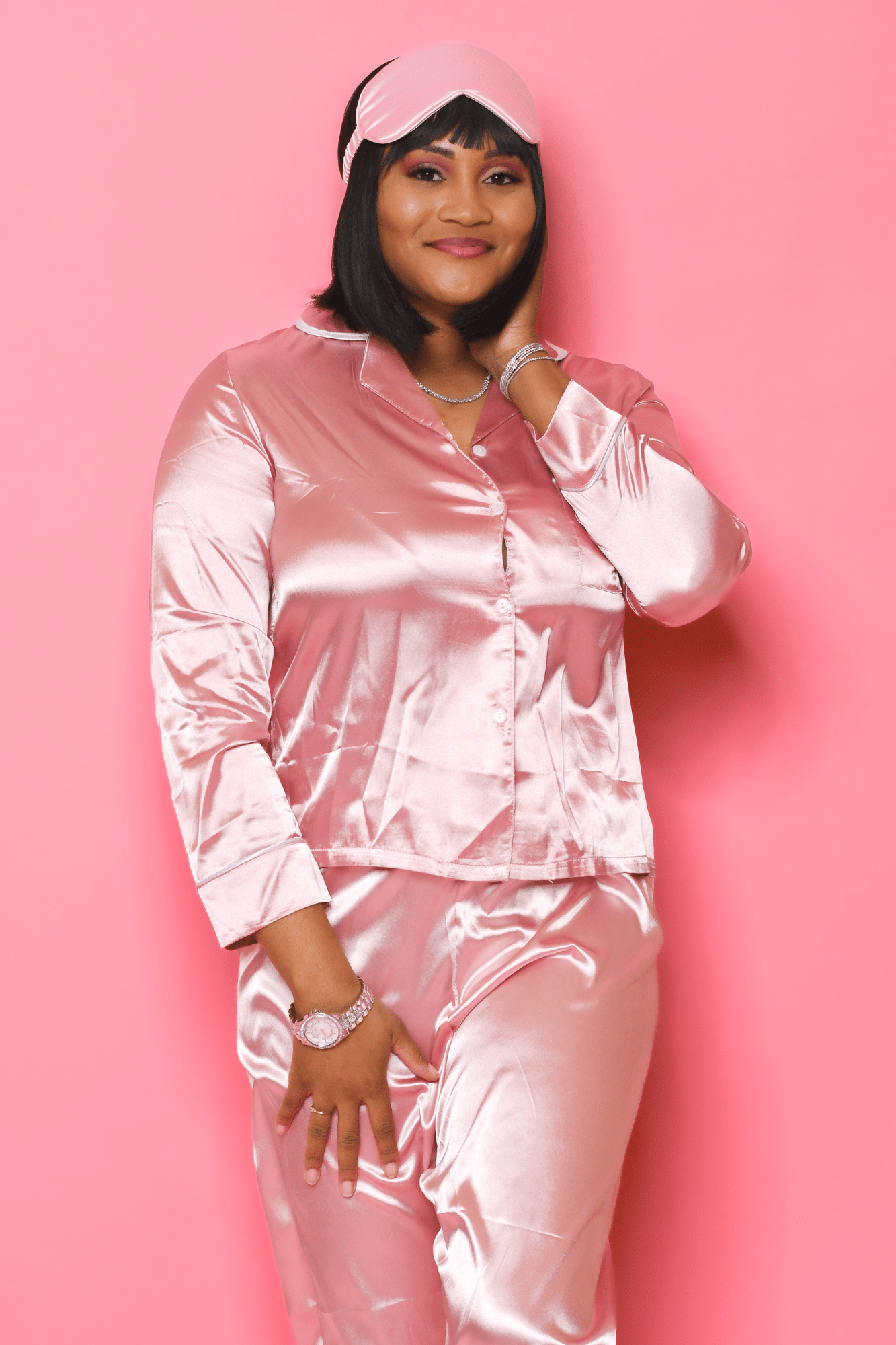 Woman wearing blush satin pajama set with button-up top and matching pants