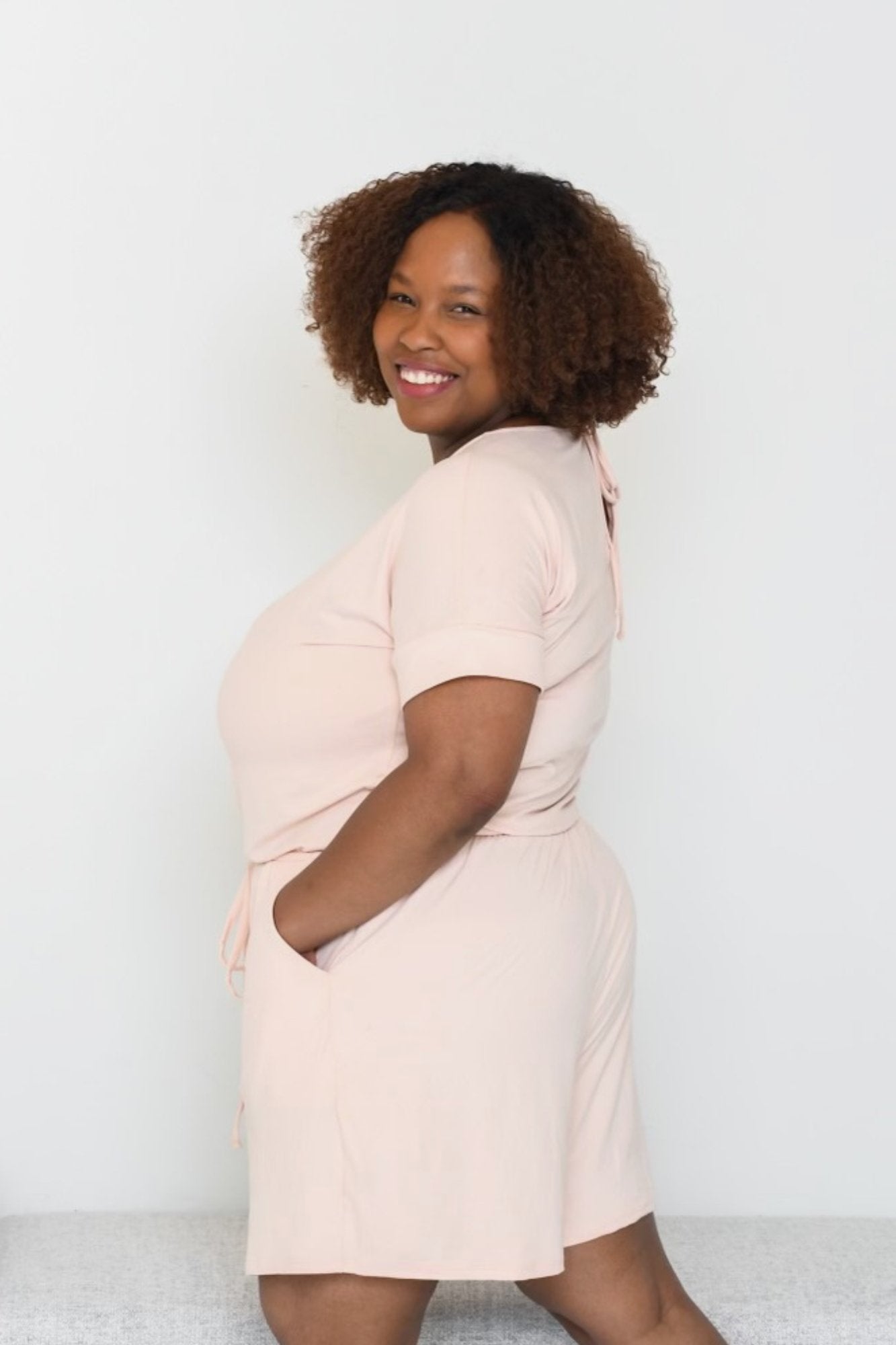 Woman wearing a cozy short-sleeve romper with a relaxed fit, drawstring waist, and side pockets. Comfortable one-piece outfit for lounging, running errands, or casual everyday wear.
