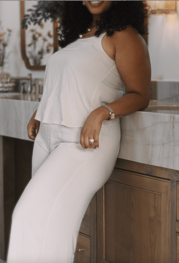 Woman in a white outfit standing in a bathroom.